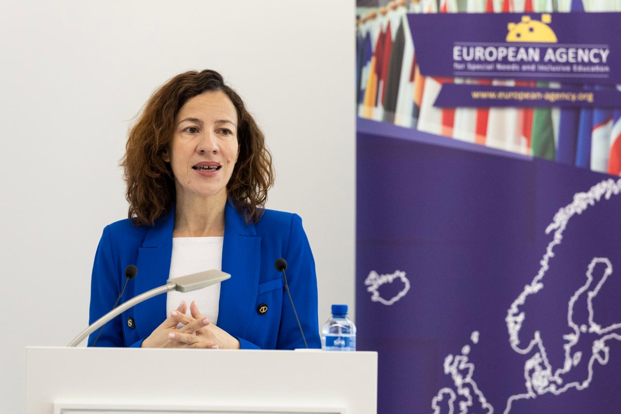 Executive Vice-President Roxana M?nzatu speaking into a microphone with EASNIE's logo behind her